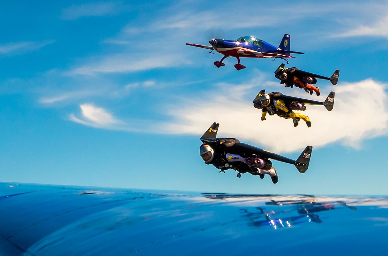 Les trois Jetman, Yves Rossy, Fred Fugen et Vince Reffet en formation serrée avec un Alphajet de la Patrouille de France ﬁlmé par Eric Magnan à bord d’un Extra 330 de l’équipe de voltige de l’armée de l’Air, actuelle championne du monde de voltige. 